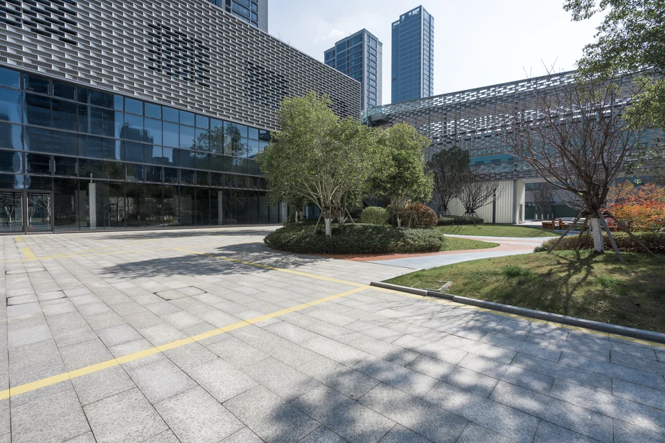 Jardin paysager en terrasses avec parterres de fleurs colorées disposés en motifs géométriques, allées courbes pavées, pelouses entretenues et arbustes taillés